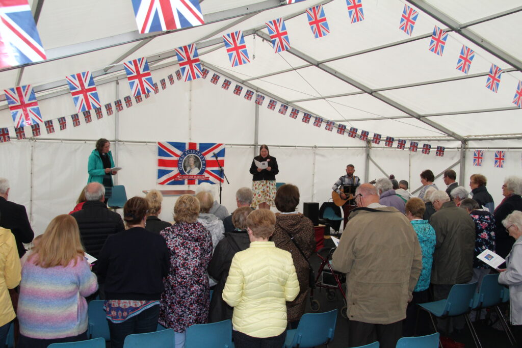 Photo of church ministers leading the jubilee service, with community watching.