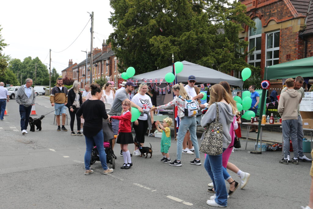 photo of the main road in shavington with a stall decorated and people walking around.