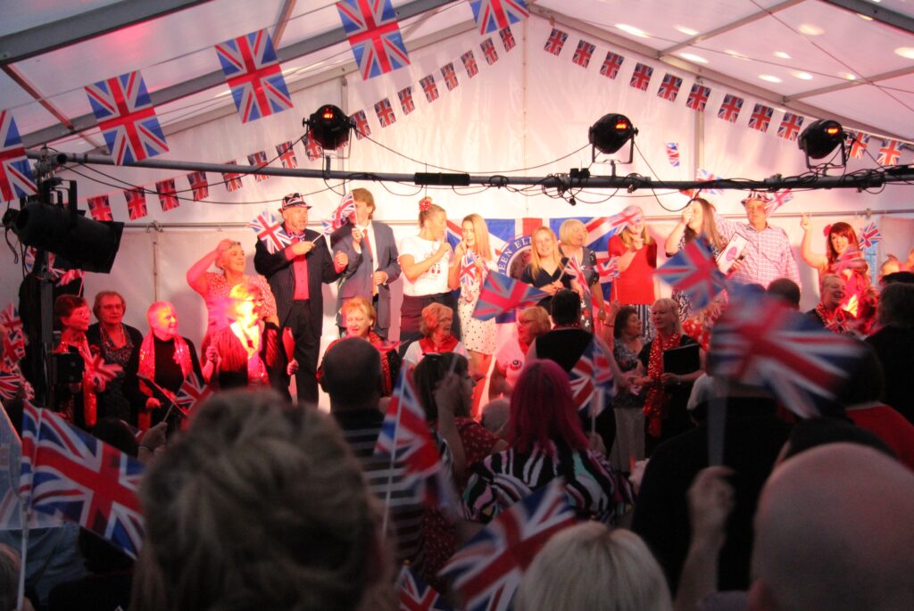 Photo of concert in full swing with stage full and audience on their feet dancing.